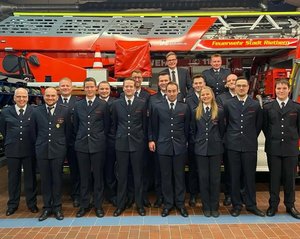 Sämtliche beförderte Feuerwehrkameraden stellen sich vor einem Löschfahrzeug in der Gerätehalle zu einem Gruppenbild auf.