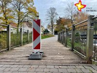 Eine Warnbake steht mittig auf einer hölzernen Brücke.