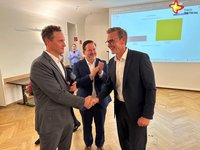 Die drei Genannten stehen in der Wahllobby. Florian Kapp gibt Andreas Sunder die Hand.