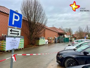 Ein blaues Schild mit einem großen P steht am Rande vor mehreren parkenden Autos.