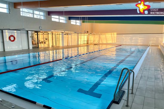 Blick in das Hallenbad auf das Wasser.