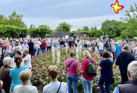 Etwa 50 Menschen stehen im Gartenschaupark zwischen Blumenbeeten und hören Bürgermeister Andreas Sunder zu.