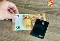 Eine Hand legt einen 50-Euro-Schein auf den Tisch, eine schwarze Visa-Karte liegt daneben.
