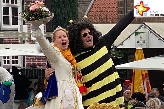 Bürgermeister Andreas Sunder steht als Biene verkleidet gemeinsam mit Prinzessin Carina I. Pahlsmeyer auf einem Karnevalswagen, der durch die Rathausstraße fährt.