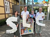 Die genannten Personen halten die Buchstaben SLC in den Händen und schauen in die Kamera.