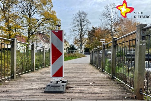 Eine Warnbake steht mitten auf einer hölzernen Brücke.