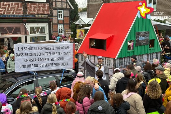 Karnevalswagen mit einer nachgebildeten Gaststätte aus Fachwerk. Der Giebel ist grün, das Dach rot.