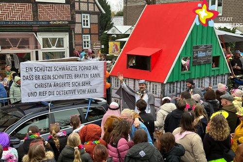 Karnevalswagen mit einer nachgebildeten Gaststätte aus Fachwerk. Der Giebel ist grün, das Dach rot.