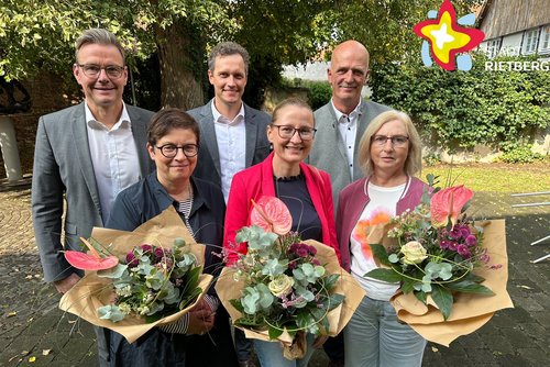 Die genannten Personen stehen im Garten und schauen in die Kamera. Die Jubilarinnen halten Blumensträuße in den Händen.
