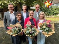 Die genannten Personen stehen im Garten und schauen in die Kamera. Die Jubilarinnen halten Blumensträuße in den Händen.