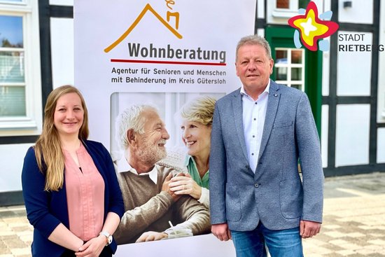 Wilfried Dörhoff, Leiter der städtischen Abteilung Jugend, Soziales & Wohnen, und AWO-Mitarbeiterin Lisa Wink stehen neben einem Werbeplakat mit der Aufschrift "Wohnberatung".