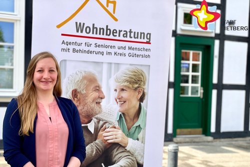 Lisa Wink steht vor einem Plakat mit der Aufschrift "Wohnberatung".