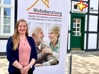 Lisa Wink steht vor einem Plakat mit der Aufschrift "Wohnberatung".