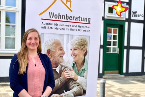Lisa Wink steht vor einem Roll-Up mit der Aufschrift "Wohnraumberatung".