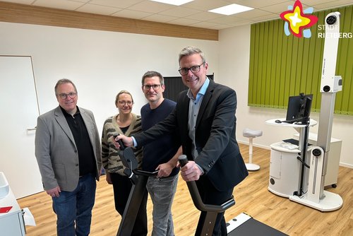 Die genannten Personen stehen in der Praxis in einem Behandlungsraum und schauen in die Kamera.