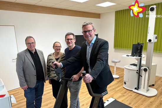 Die genannten Personen stehen in der Praxis in einem Behandlungsraum und schauen in die Kamera.