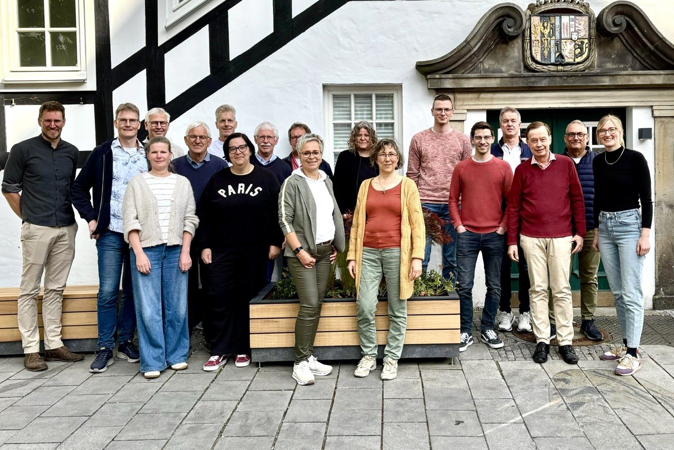 Eine Reihe Frauen und Männer stehen nebeneinander vor einer Fachwerk-Fassde und lächen in die Kamera.