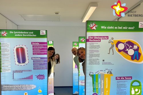 Die genannten Personen stehen zwischen großen Ausstellungswänden und schauen in die Kamera.