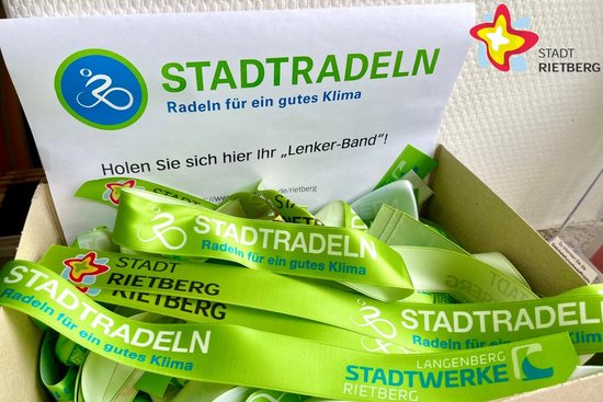 In einer Kiste liegen mehrere grüne Bänder mit der Aufschrift "Stadtradeln" durcheinander.