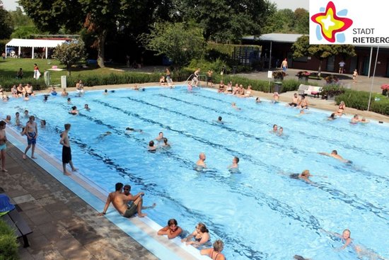 Ein Sommertag im Freibad. Badegäste schwimmen im Becken. Die Sonne scheint.