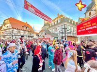 Unter blauem Himmel ist der Platz vor dem Historischen Rathaus mit bunt kostümierten Menschen gefüllt.