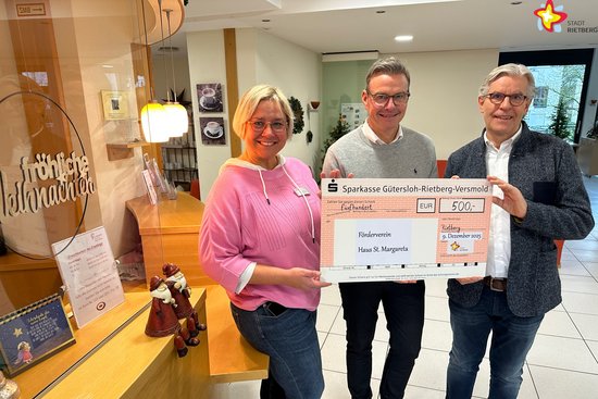 Die genannten Personen stehen im Foyer des Altenheims und halten einen großen Scheck in die Kamera.