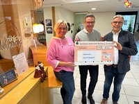 Die genannten Personen stehen im Foyer des Altenheims und halten einen großen Scheck in die Kamera.