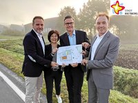 Die Prokuristen der Karl Brand KG, Thorsten Seitz und Jürgen Lingstädt halten gemeinsam mit Wirtschaftsförderin Renate Pörtner und Bürgermeister Andreas Sunder an dem neuen Grundstück an der Mastholter Straße einen Langeplan für den künftigen Firmensitz in den Händen.