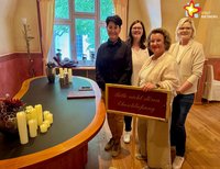Vier Frauen stehen neben einem geschwungenen Tisch mit Kerzen darauf.