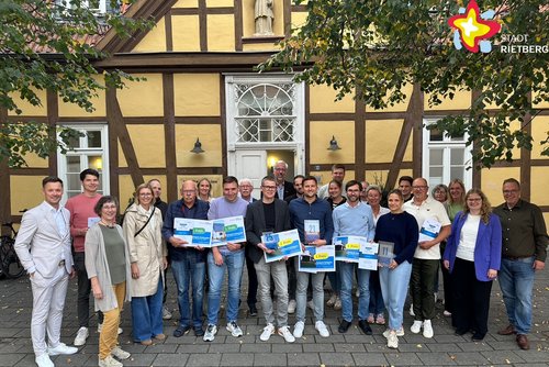Eine Gruppe von Personen steht vor dem Alten Progymnasium und hält die Blauen Hausnummern in Händen.