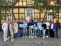 Eine Gruppe von Personen steht vor dem Alten Progymnasium und hält die Blauen Hausnummern in Händen.