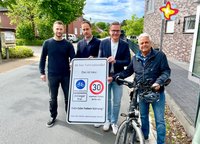 Christian Kleinhans, Nils Kutscher und Andreas Sunder halten gemeinsam ein etwa einMeter hohes Schild mit der Aufschrift "Fahrradstraße". Rechts daneben steht Hermann Lütkebohle neben seinem Fahrrad.