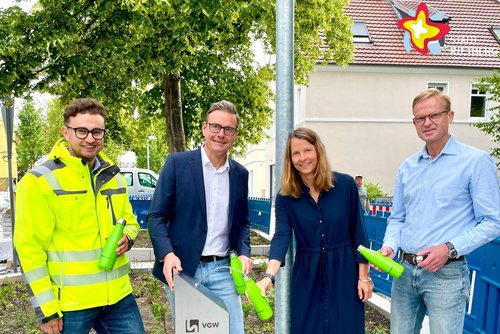 Jan Stephan, Bürgermeister Andreas Sunder, Dr. Gesa Kutschera und Dr. Carsten Behlert stehen hinter einem Trinkwasserspender an einem Radweg. Jeder hält eine grüne Flasche in der Hand, die sie mit Wasser füllen.