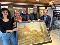 Die genannten Personen halten ein Ölgemälde in die Kamera und lächeln. Es zeigt das Rietberger Kloster. Im Hintergrund hängen drei weitere Bilder an einer Wand.