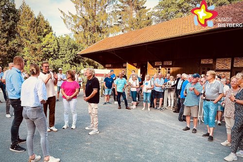 Die genannten Personen und viele weitere stehen vor einer Scheune auf dem Hof.