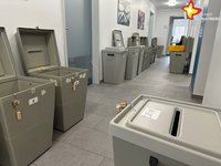 Einige graue Wahlurnen stehen aufgereiht nebeneinander auf dem Flur des Rathauses. Teilweise sind die Deckel aufgeklappt.