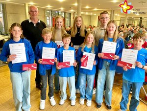 Junge und ältere Sportlerinnen und Sportler stehen mit Urkunden in den Händen in zwei Reihen nebeneinander.