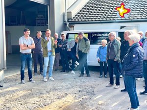 Bürgermeister Andreas Sunder und Parkettlegemeister Jens Berenbrink stehen mit mehreren Zuhörern vor einer geöffneten Firmenhalle.