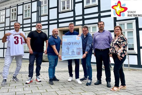 Bülent Subasi, Ahmet Tümay, Zeki Altunay, Bürgermeister Andreas Sunder, Beigeordneter Andreas Göke, Ercan Bediroglu und Sabine Kovar halten gemeinsam ein Werbeplakat für die interkulturelle Benefizveranstaltung am Sonntag.