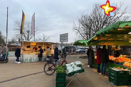 Das Foto zeigt zwei Wochenmarkt-Stände mit Auslagen.