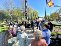 Gäste stehen rund um den Handwerkerbaum in Mastholte auf dem neuen Platz. Die Sonne scheint, der Himmel ist blau.