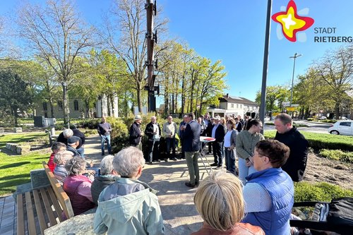 Gäste stehen rund um den Handwerkerbaum in Mastholte auf dem neuen Platz. Die Sonne scheint, der Himmel ist blau.