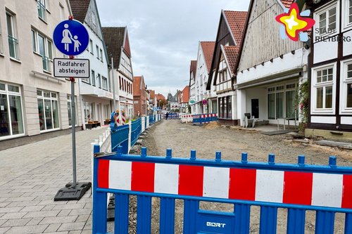 Eine Warnbake steht vor einer im Bau befindlichen Straße. Links der Fußweg ist bereits ordentlich gepflastert.