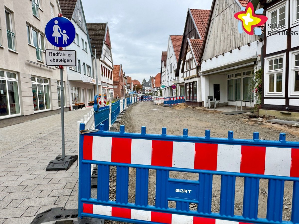 Eine Warnbake steht vor einer im Bau befindlichen Straße. Links der Fußweg ist bereits ordentlich gepflastert.