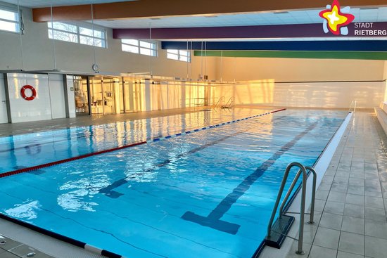 Zu sehen ist ein menschenleeres Schwimmbecken mit blau schimmerndem Wasser.