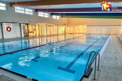 Zu sehen ist ein menschenleeres Schwimmbecken mit blau schimmerndem Wasser.
