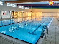 Zu sehen ist ein menschenleeres Schwimmbecken mit blau schimmerndem Wasser.