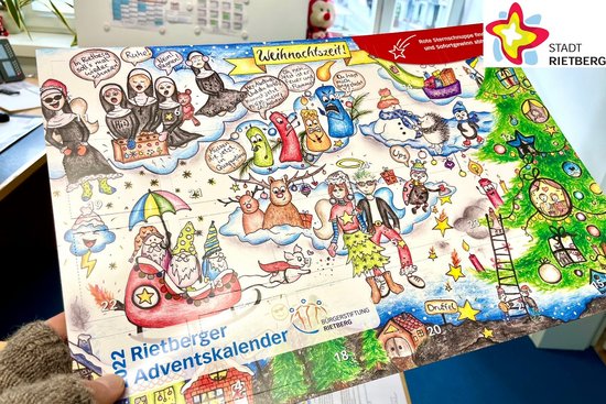 Zwei Hände halten den Adventskalender 2022 in die Kamera, der wie ein Wimmelbild zahlreiche weihnachtliche Motive zeigt.