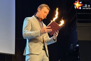 Zauberer Daniel Dück lässt Flammen aus einem Buch schießen.