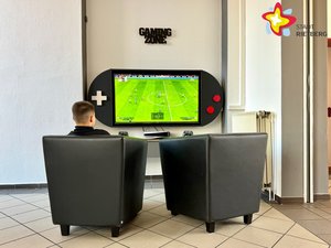 Zwei Sessel stehen vor einem Bildschirm mit einer grünen Fußballfläche.